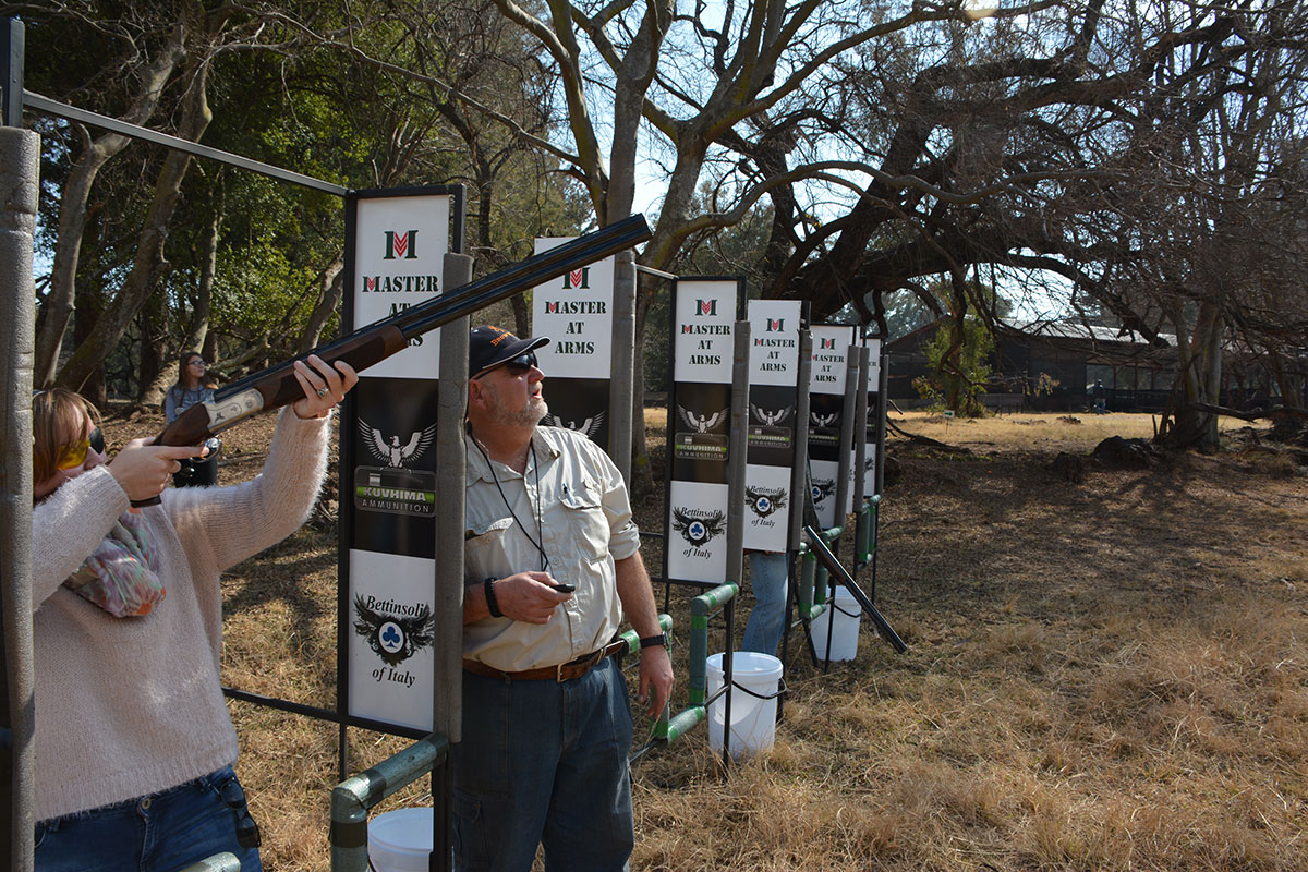 Shooter aiming at clay target with Master at Arms coach